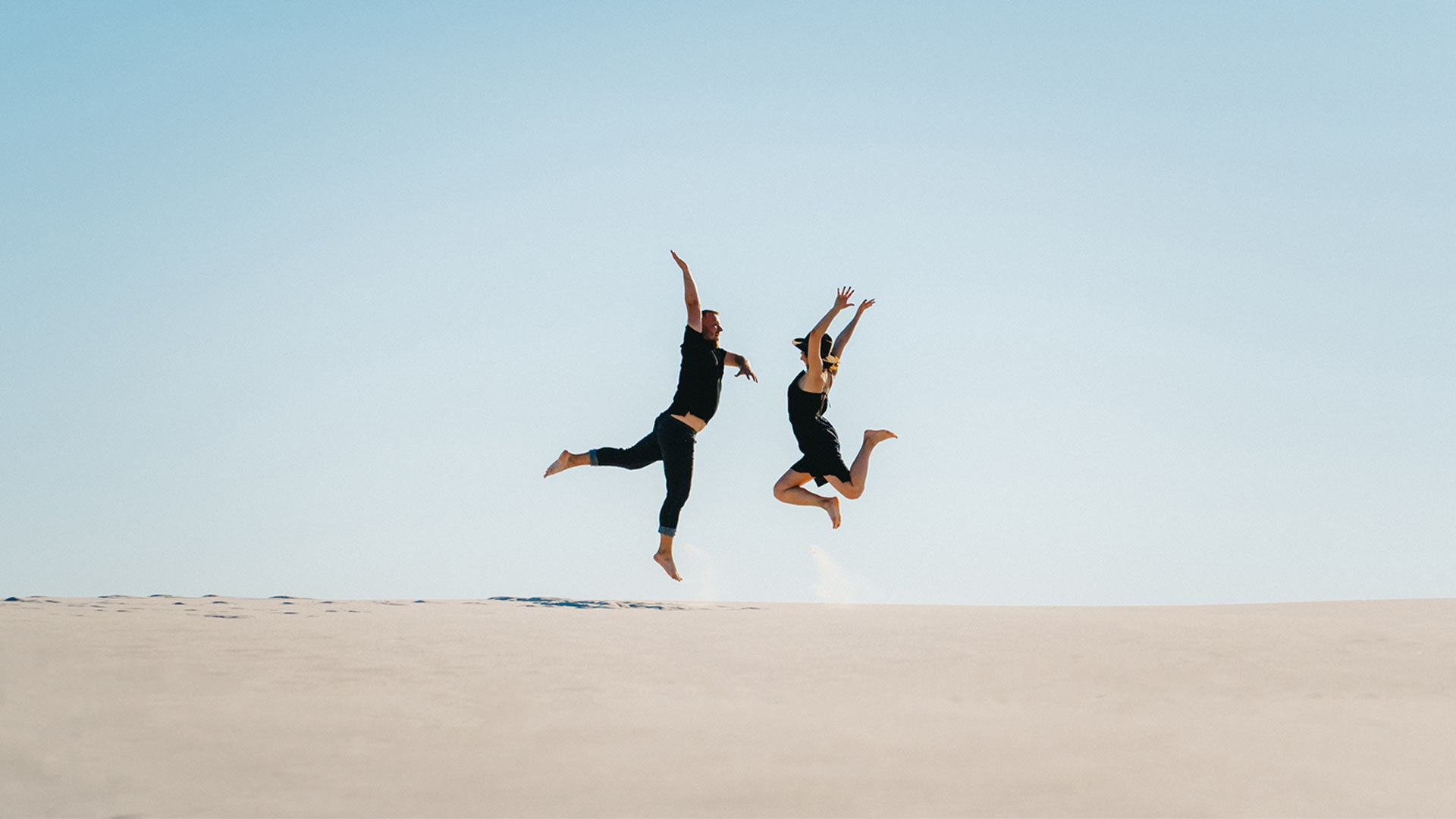 Couple jumping up high on a beach feeling positive benefits of raised NAD levels